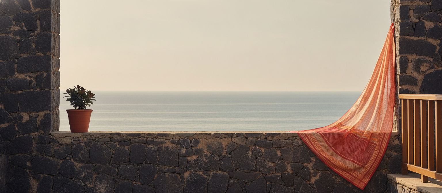 Peach Kota Doria Cotton Checks Saree with jacquard border draped on a stone wall, overlooking a serene ocean under a clear sk